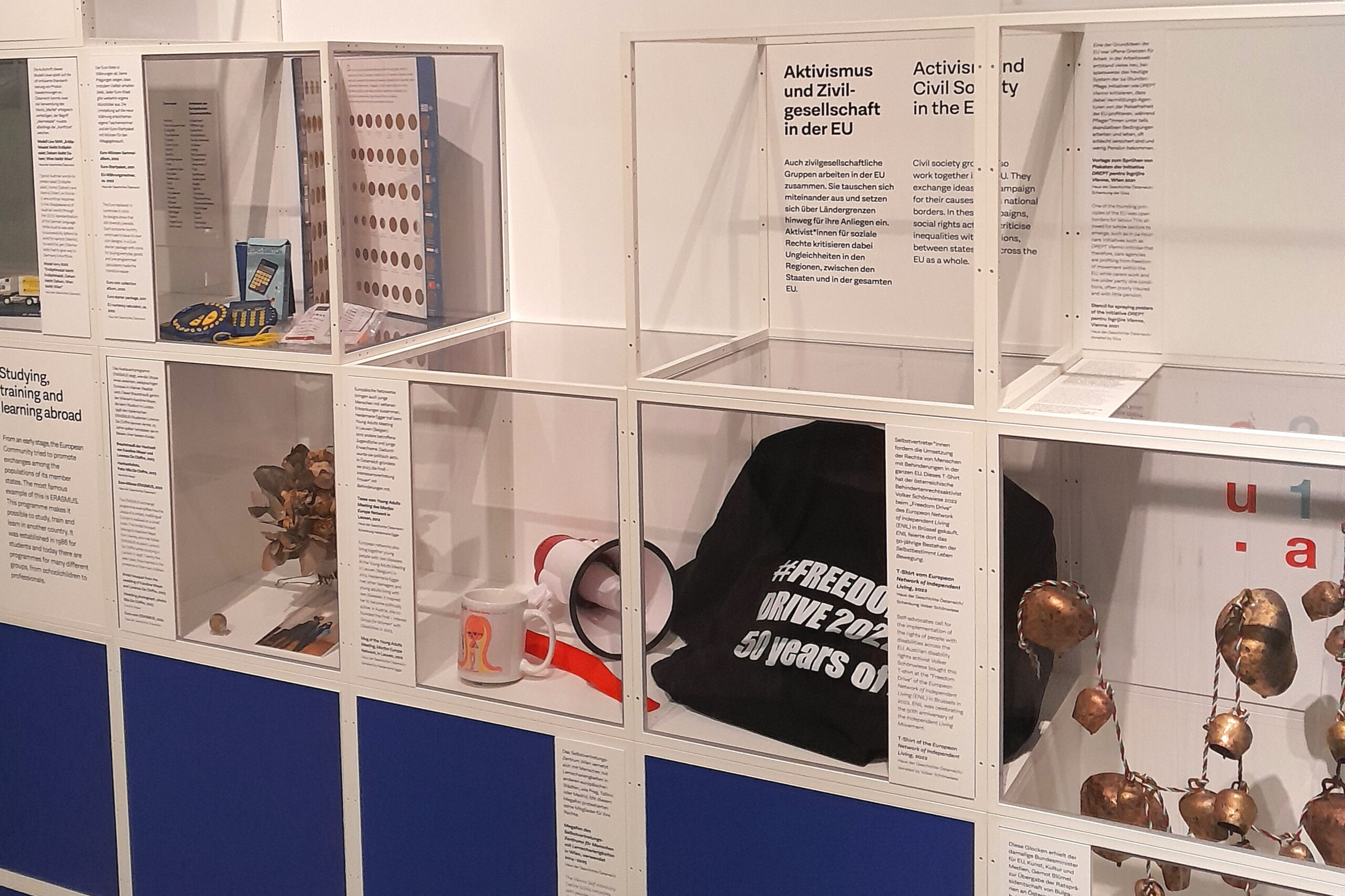 Mehrere Objekte einer Ausstellung werden in einem Glaskasten mit einigen Fenstern zur Schau gestellt.