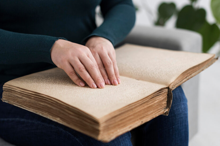 Eine Frau fährt mit beiden Händen über die Punkte in einem Buch in Braille-Schrift