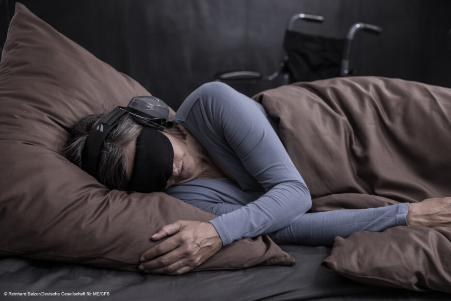 ME CFS © Reinhard Balzer Deutsche Gesellschaft fuer ME CFS Eine Frau liegt in einem abgedunkelten Raum im Bett und trägt dabei Kopfhörer und eine Schlafmaske
