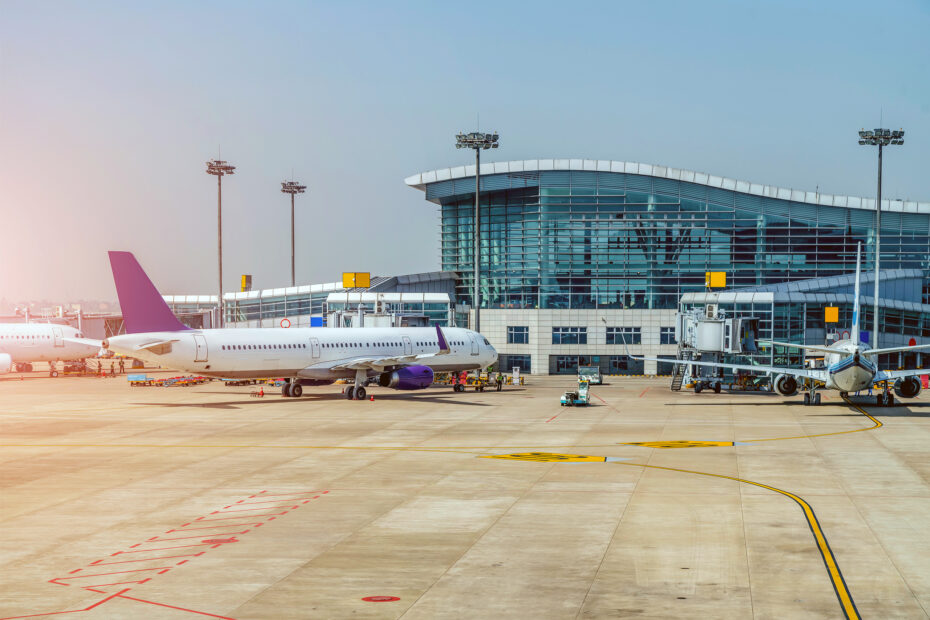 Flughafen © Magnific Flughafen von außen: Es stehen drei Flugzeuge an Terminals, im Hintergrund ist ein gläsernes Gebäude zu sehen