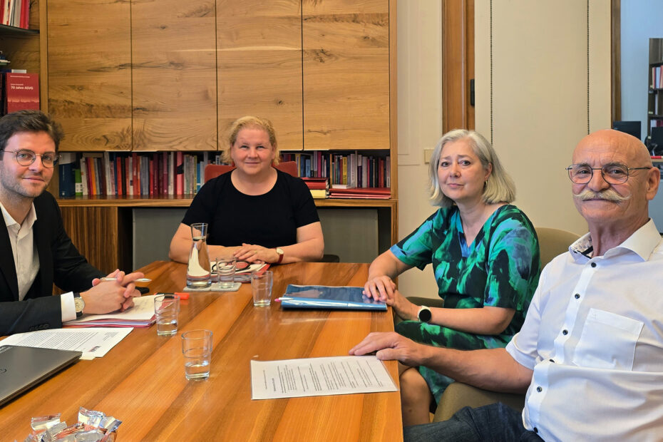 Treffen mit Sozialministerin Korinna Schumann Zwei Männer und zwei Frauen sitzen an einem viereckigen Tisch und lächeln in die Kamera. Der Mann, der links sitzt, trägt eine Brille und hat braunes Haar. Am Kopfende sitzt Sozialministerin Korinna Schumann, sie hat kurzes, blondes Haar. Auf der rechten Seite sitzen Regina Baumgartl und Franz Groschan, Generalsekretärin bzw. Präsident des KOBV Österreich - Der Behindertenverband. Baumgartl hat mittellanges, graues Haar, Groschan ist Bart- sowie Brillenträger und hat eine Glatze.